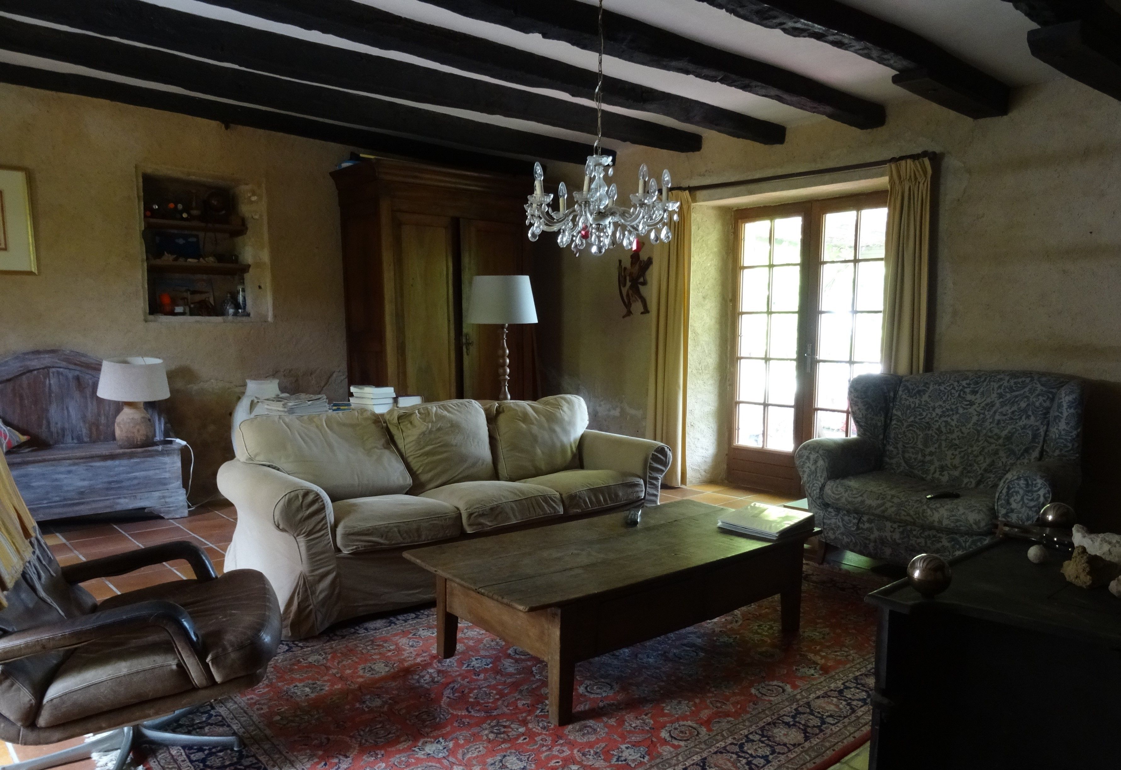 A living room with a sofa, armchair, coffee table, and a chandelier.