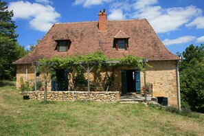 A stone house with a tiled roof, two windows, and a covered porch with vines. - Holiday Home 'Les Essarts, La Ferme' with Shared Pool, Private Terrace and Wi-Fi (Plazac)