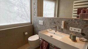 A modern bathroom with a large mirror, a dual sink vanity, and a toilet. - Rex Palast (Memmingen)