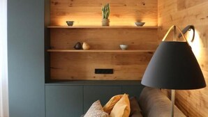 A modern living room with a wooden wall unit, a sofa with cushions, and a floor lamp. - Rex Palast (Memmingen)
