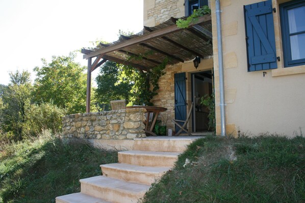A stone staircase leading to a wooden porch with a table and chairs.