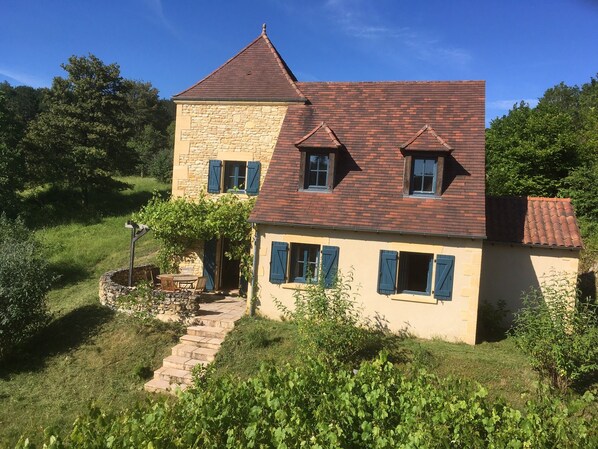 Ein zweistöckiges Haus mit einer Stein-Fassade und einem roten Ziegeldach.