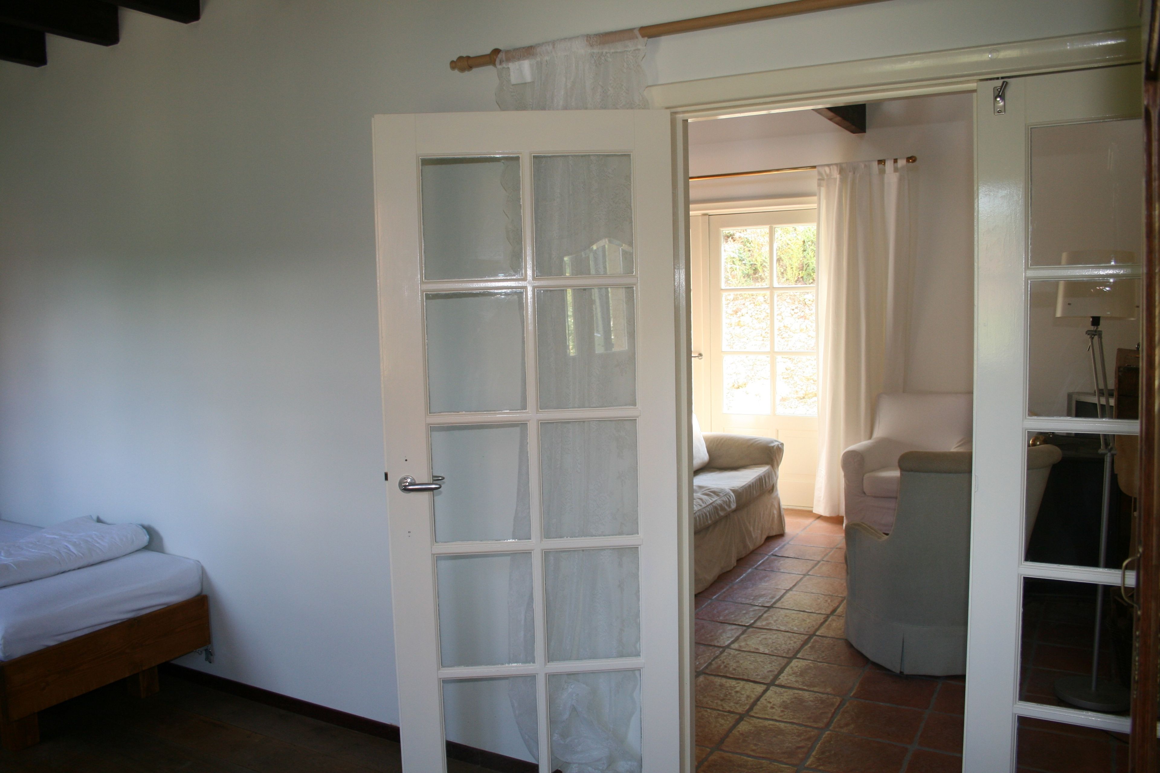 Une pièce comprenant un lit, une chaise et une porte donnant sur une autre pièce.