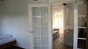 Une pièce comprenant un lit, une chaise et une porte donnant sur une autre pièce.