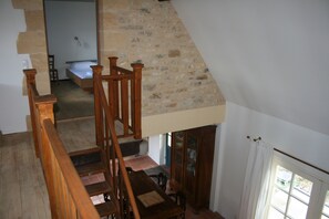 A staircase leading to a bedroom with a stone wall and a wooden railing.