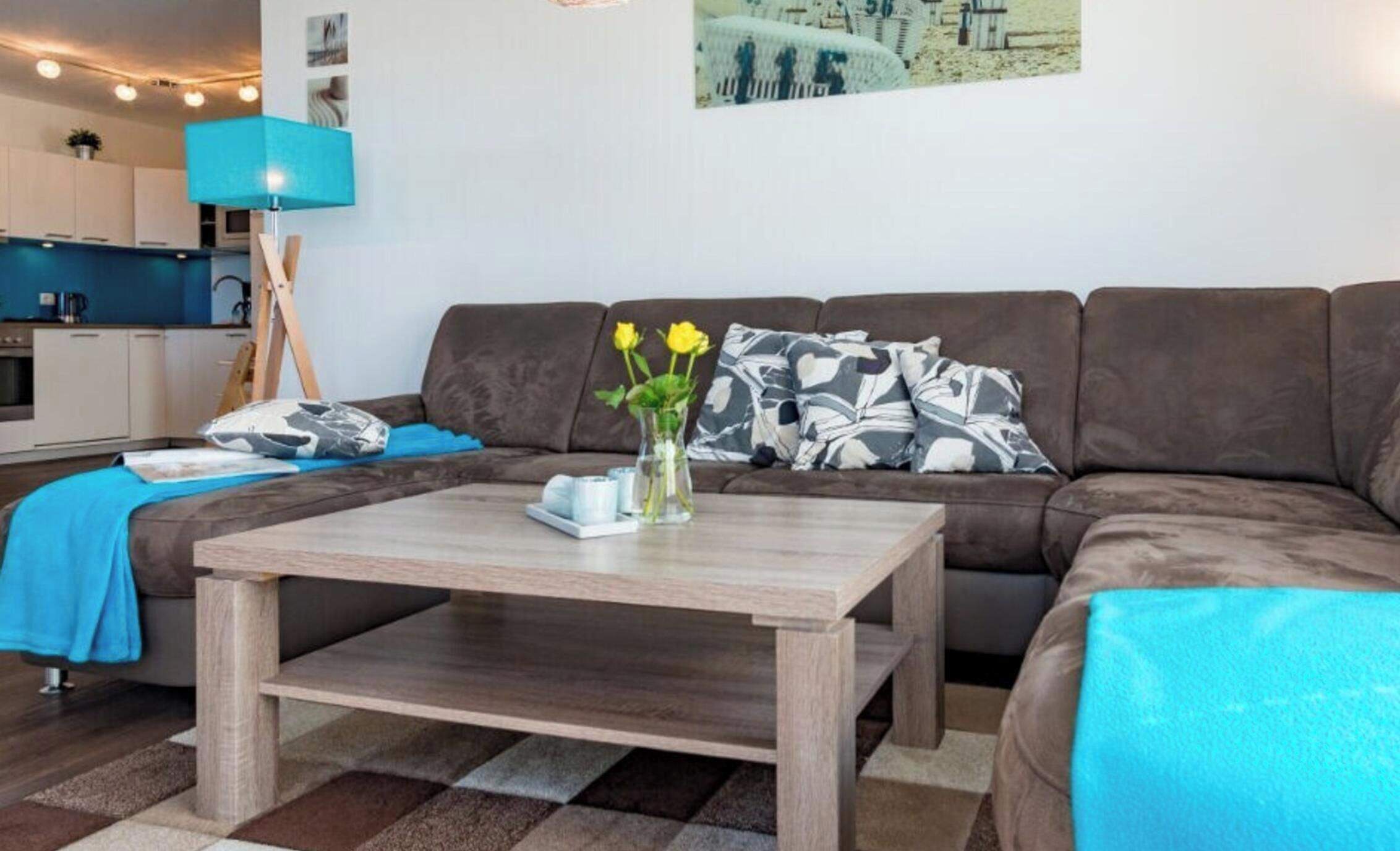 A modern living room with a brown sofa, a wooden coffee table, and a blue blanket.