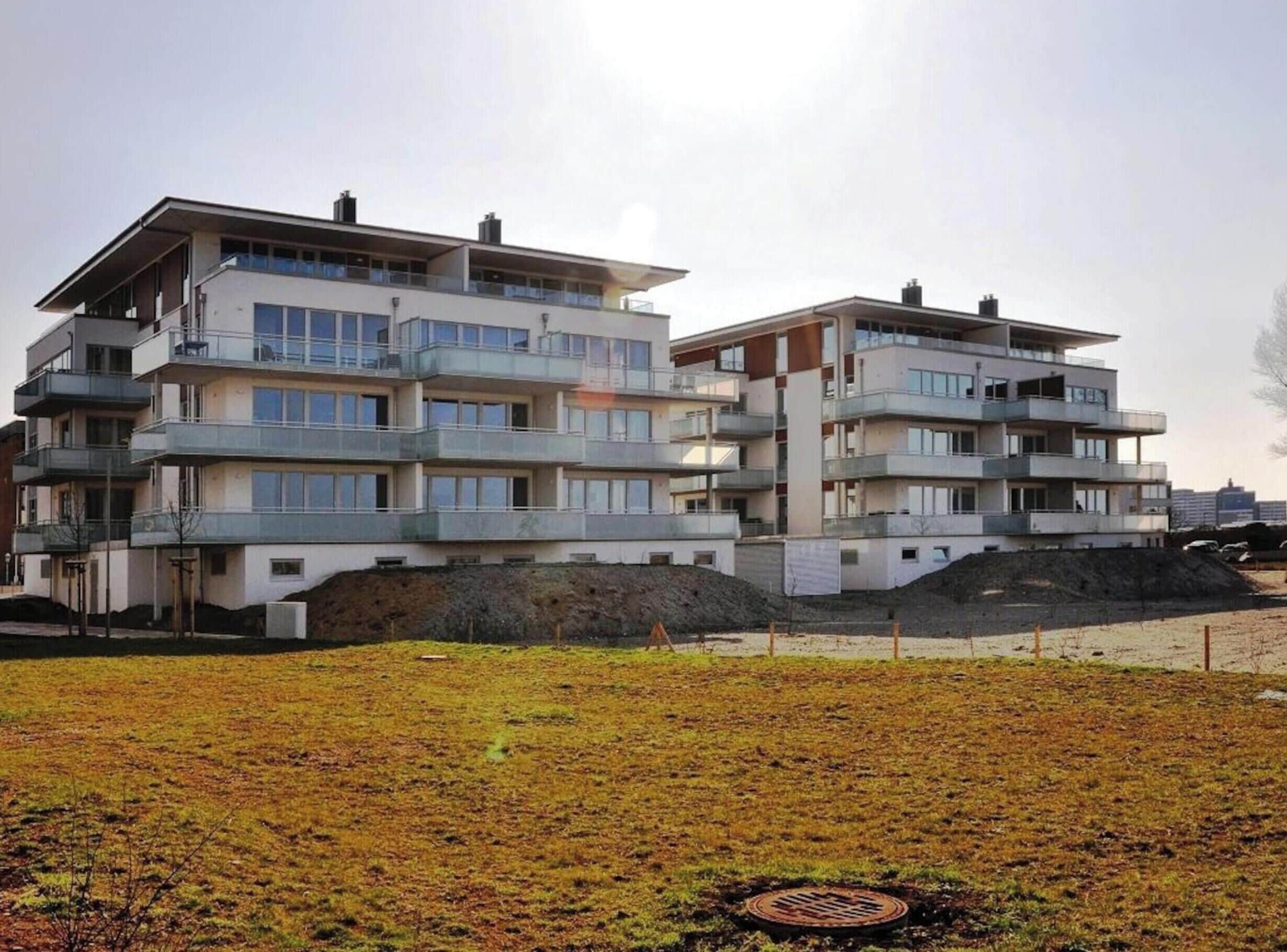 Un edificio residenziale a più piani con balconi, tetto piano e un cantiere in primo piano.
