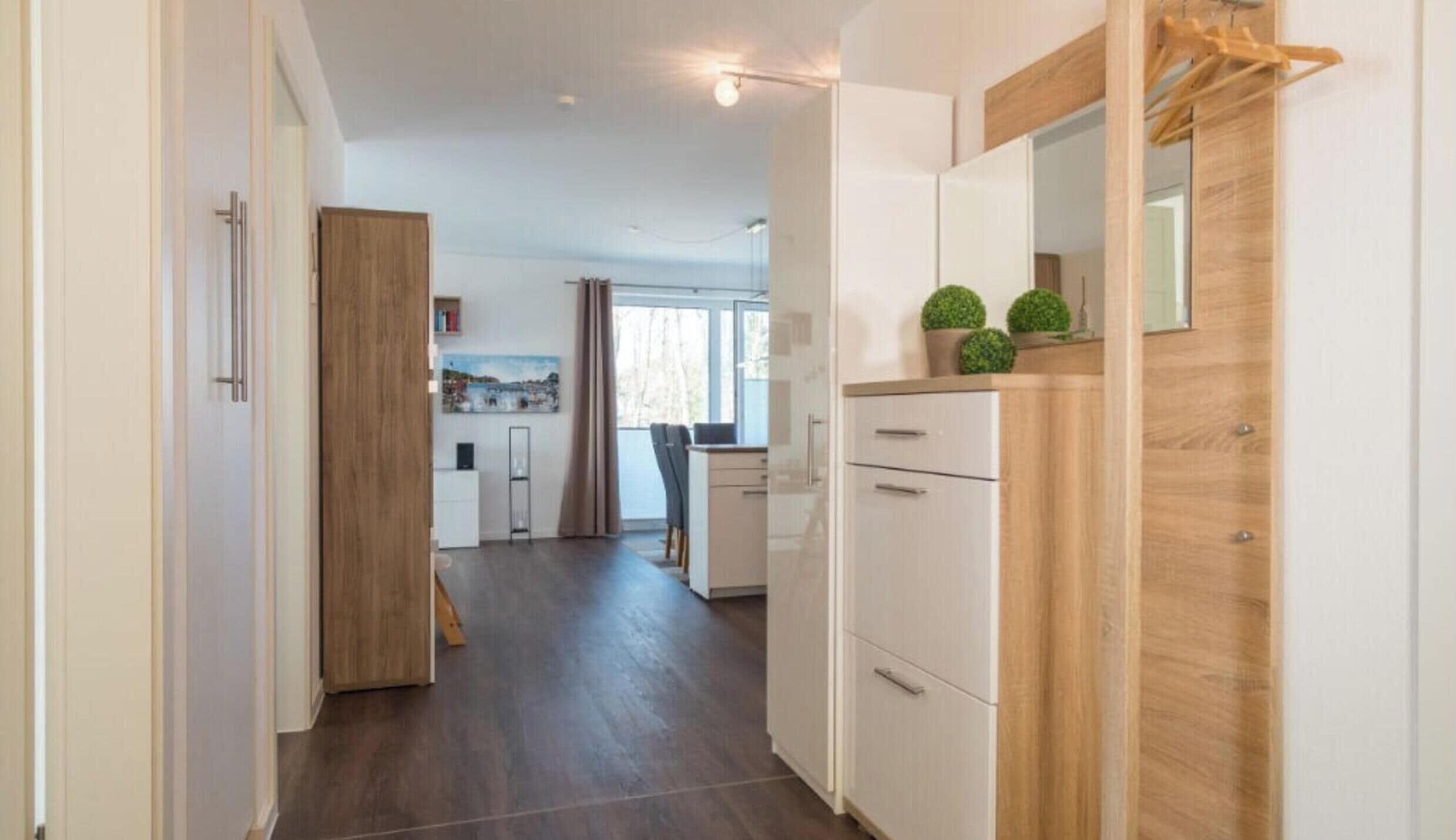 A modern kitchen with white cabinets, a wooden countertop, and a small potted plant.