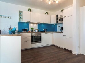 Eine moderne Küche mit weißen Schränken, einem eingebauten Backofen und einer blauen Spritzschutzwand.
