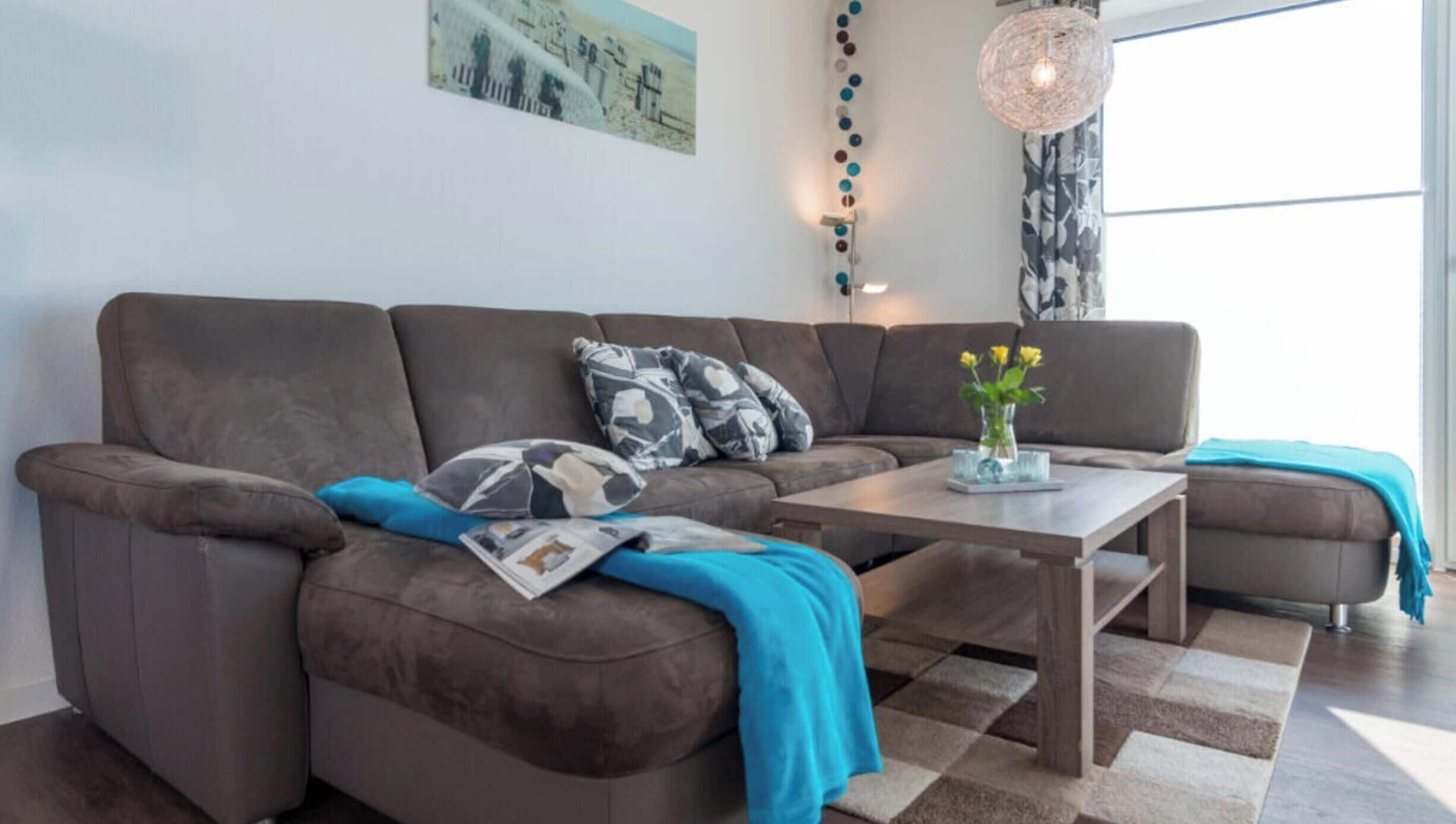 A modern living room with a sectional sofa, a coffee table, and a vase with flowers.