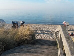 A wooden boardwalk leading to a sandy beach with calm water in the background. - Holiday Apartment With 2 Bedrooms (Heiligenhafen)