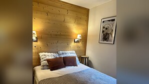 Una camera d'albergo con testiera in legno, due lampade sui comodini, un letto con copripiumino a righe e un quadro appeso al muro.