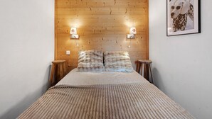 Una habitació amb un capçal de llit de fusta, dues làmpades de nit, un llit amb una manta amb textura i un quadre amb marc a la paret.