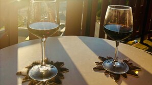 Due bicchieri di vino su un tavolo con il sole sullo sfondo.