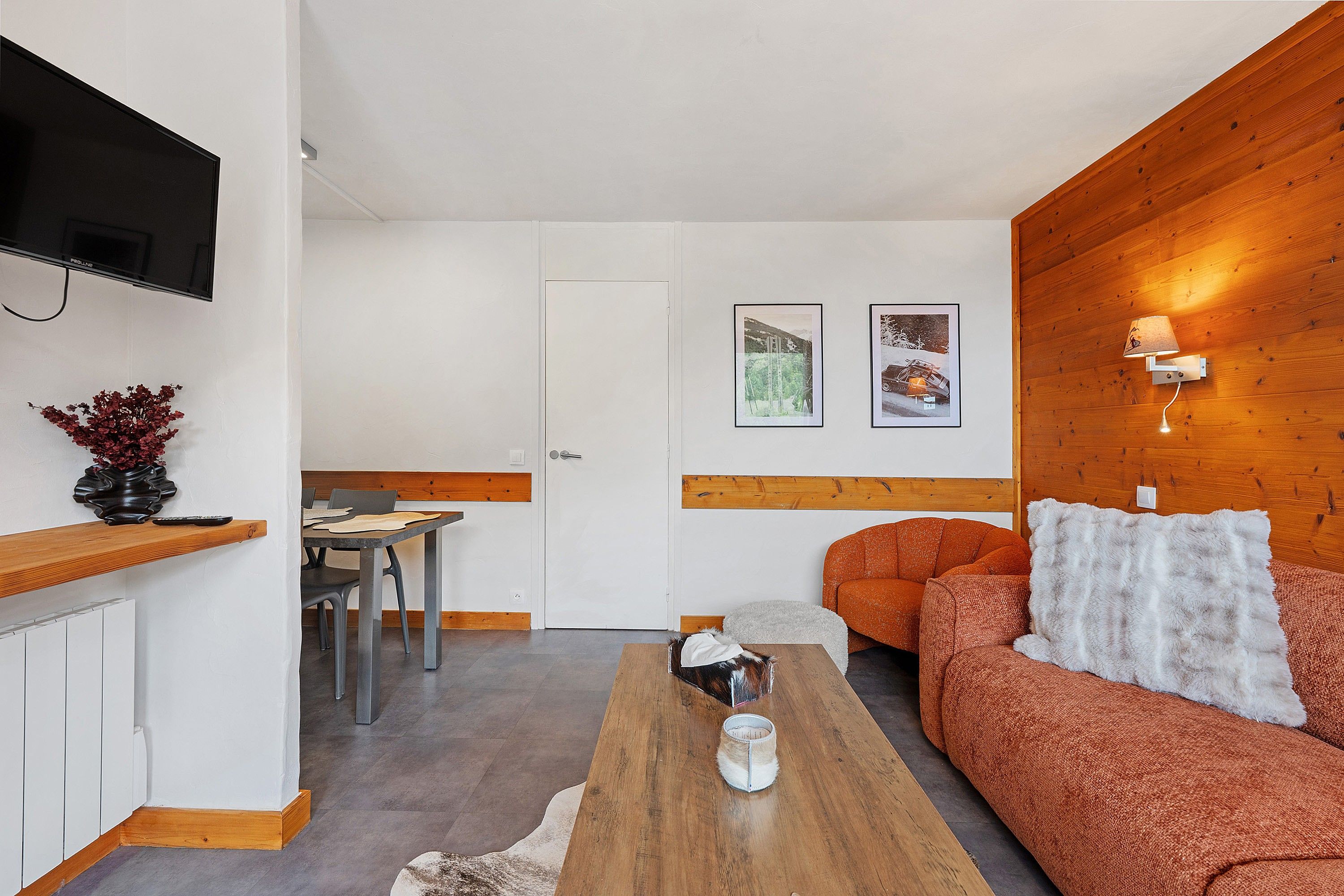 A modern living room with a wooden accent wall, a sofa, a coffee table, and a TV mounted on the wall.