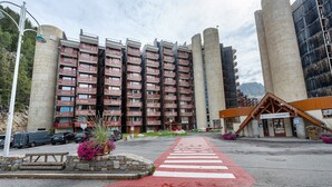 Un hotel amb un pas de vianants vermell, una zona d'aparcament i un edifici amb nombroses balcons.