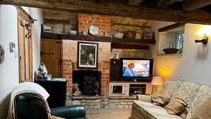 Un salon chaleureux avec une cheminée, un téléviseur, un fauteuil en cuir et un canapé à motifs.