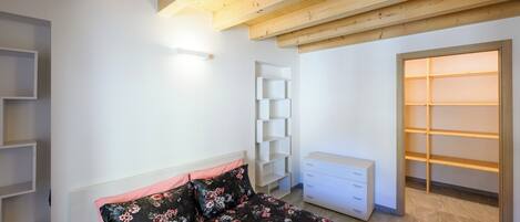 Un dormitorio con cama, cómoda, estantería y armario.
