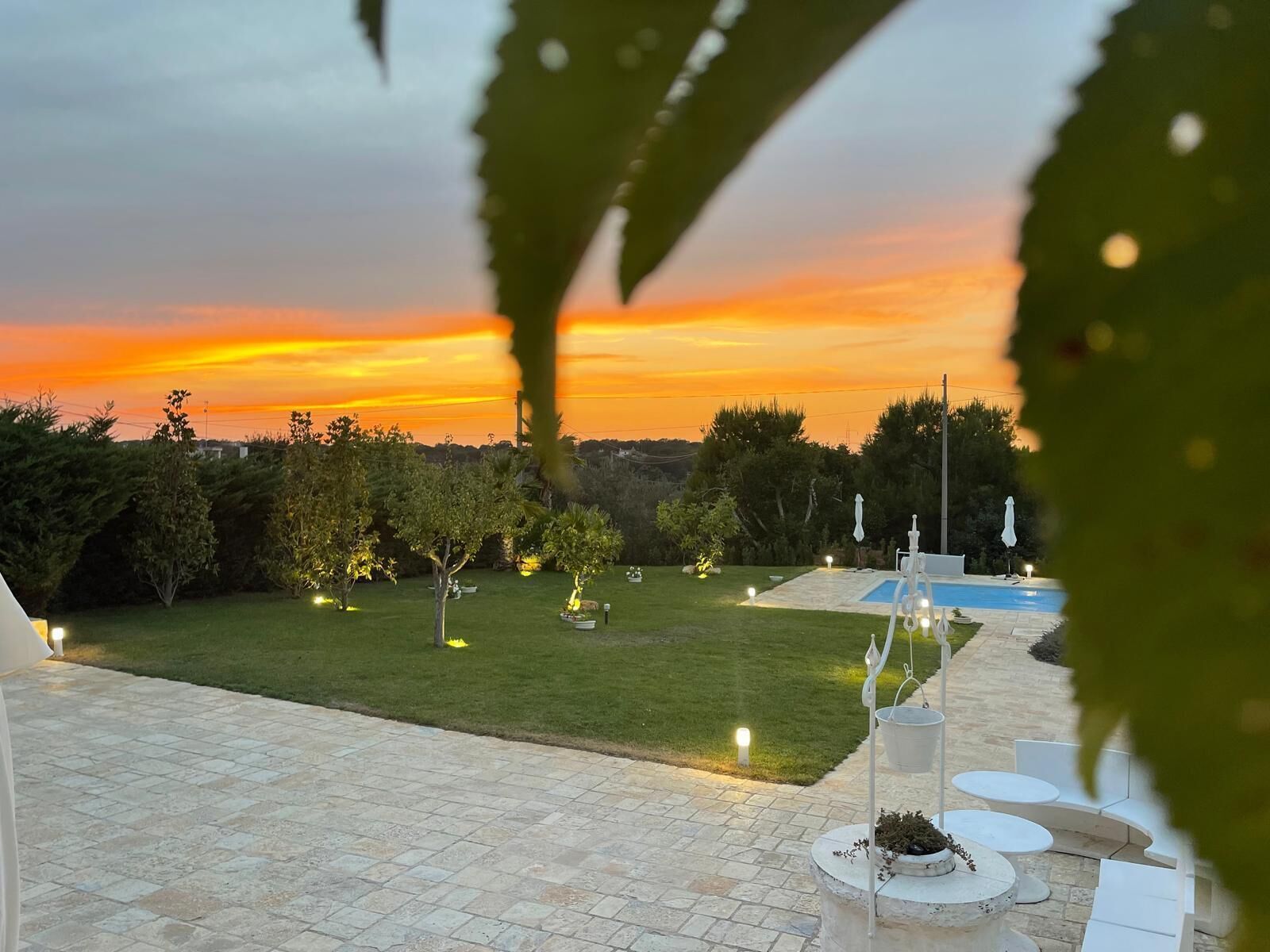 Un espace extérieur aménagé avec une piscine, des sièges et une vue imprenable sur le coucher de soleil.