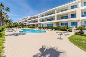 Ein Hotel mit Schwimmbad, Liegestühlen und einem gepflegten Garten.