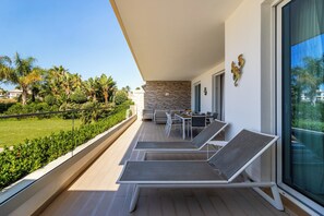 Ein moderner Balkon mit Essbereich, Lounge-Sesseln und Blick auf einen üppigen Garten.