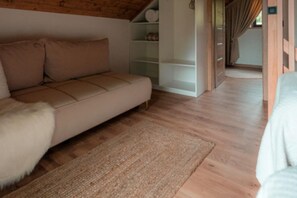 A modern interior with a sofa, a rug, wooden flooring, and a white shelving unit. - Comfortable holiday home with private jacuzzi (Rabka Zdroj)