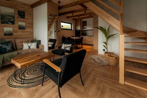 En modern inredning med en trappa i trä, en matplats och ett vardagsrum med en soffa och ett soffbord.