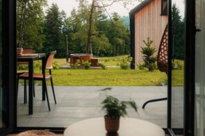 An outdoor patio area with a table and chairs, a hot tub, and a wooden deck.