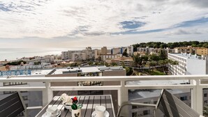 A balcony with a table set for dining, overlooking a coastal cityscape with buildings and a beach. - Studio in Costa del Sol, Torremolinos (Torremolinos)