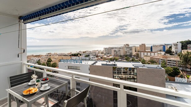 A balcony with a table set for dining, overlooking a cityscape with buildings and a distant view of the sea. - Studio in Costa del Sol, Torremolinos (Torremolinos)