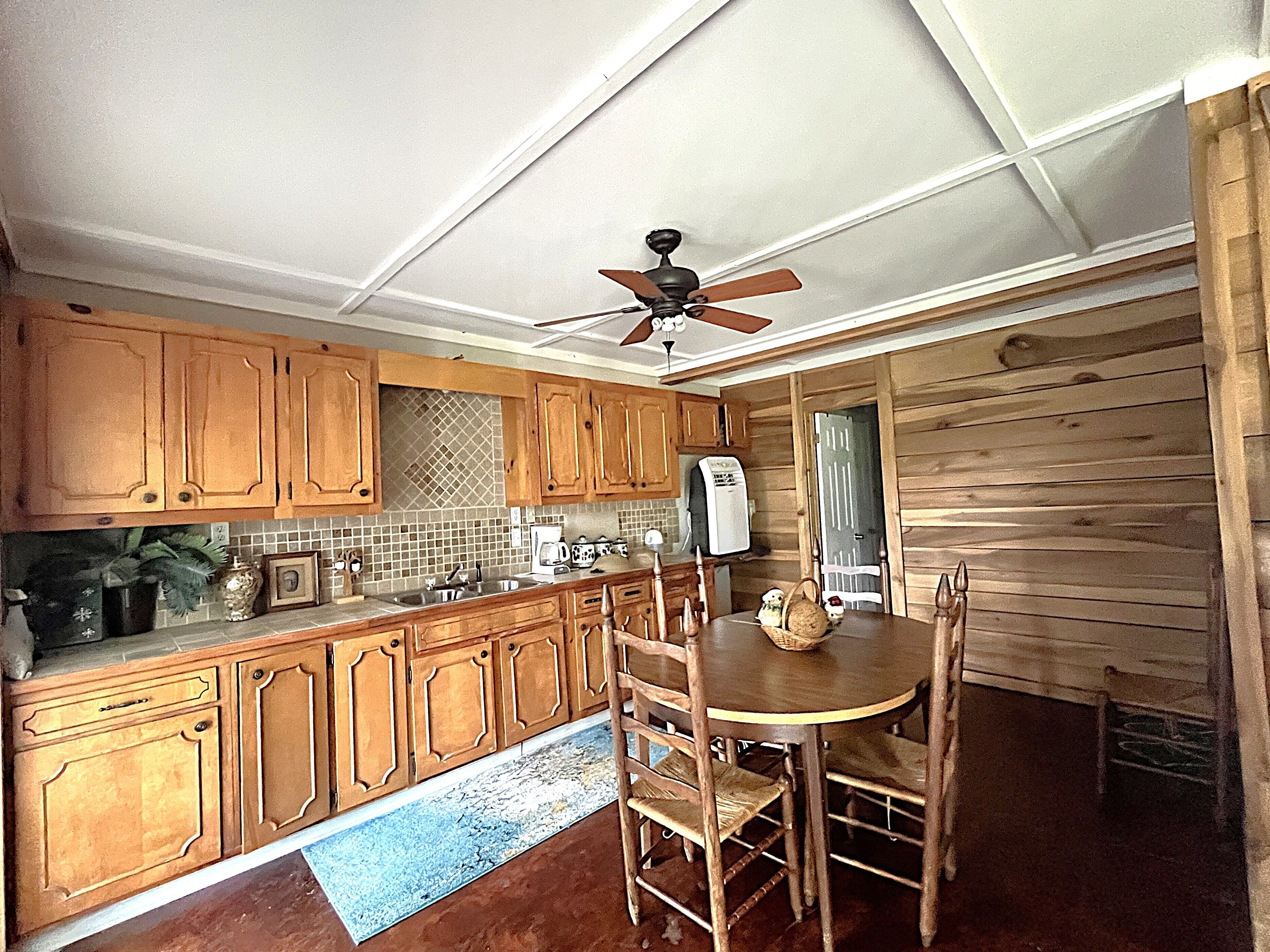 A kitchen with wooden cabinets, a dining table with chairs, and a ceiling fan.