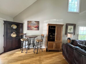 A room with a dining table and chairs, a cabinet, a sofa, and artwork on the walls. - Rustic 4 bedroom Cabin Near Safe Harbor Aqua (Iuka)
