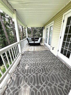 A covered porch with a patterned floor, two chairs, and a white railing. - Rustic 4 bedroom Cabin Near Safe Harbor Aqua (Iuka)