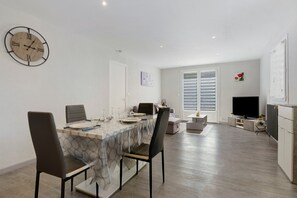 A modern dining area with a round table, chairs, and a wall clock. - Apartment "Gîte Aurives" with Mountain View, Shared Terrace and Wi-Fi (Le Cheylard)
