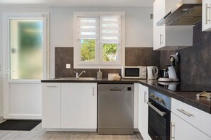Une cuisine moderne avec des meubles blancs, un lave-vaisselle encastré, un four à micro-ondes et une cuisinière.