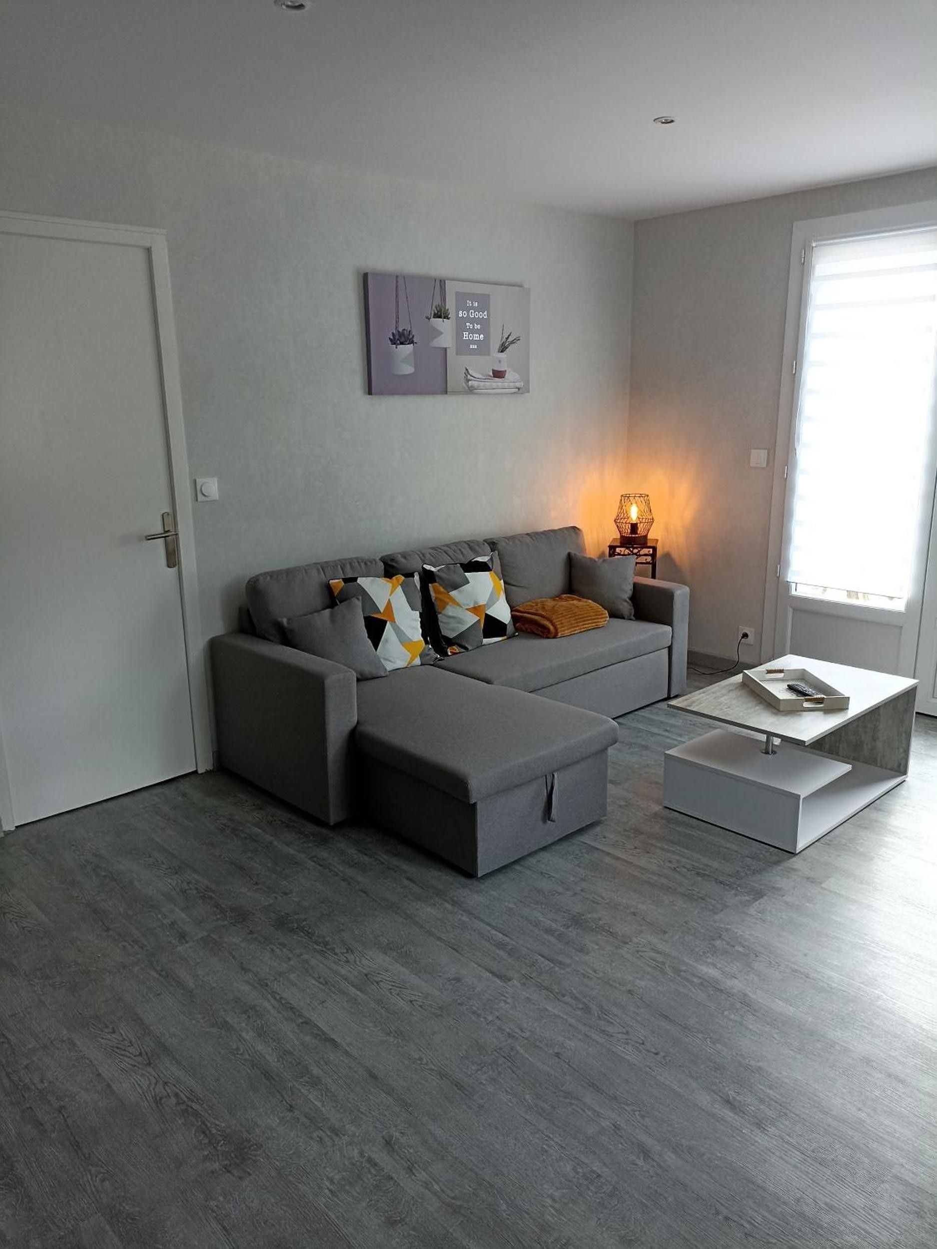 Un salon moderne avec un canapé gris, une table basse et une œuvre d’art accrochée au mur.