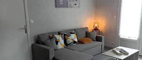 Ein modernes Wohnzimmer mit einem grauen Sofa, einem Couchtisch und einem Wandbild.
