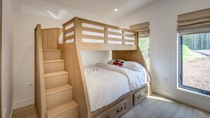 A bunk bed with a wooden ladder, a window with blinds, and a view of the outdoors. - Modern house: Hot Tub Near Skiing & Harbor Springs (Harbor Springs)