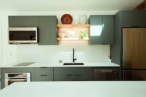 Una cocina moderna con microondas integrado, electrodomésticos de acero inoxidable y un armario de madera.