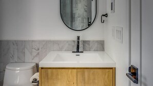 A modern bathroom with a white toilet, a wooden vanity with a sink, and a mirror above the sink. - Modern house: Hot Tub Near Skiing & Harbor Springs (Harbor Springs)