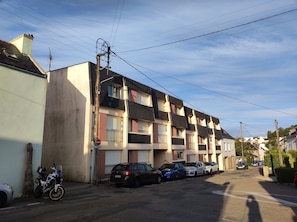 Una calle residencial con casas adosadas, coches aparcados y una motocicleta.