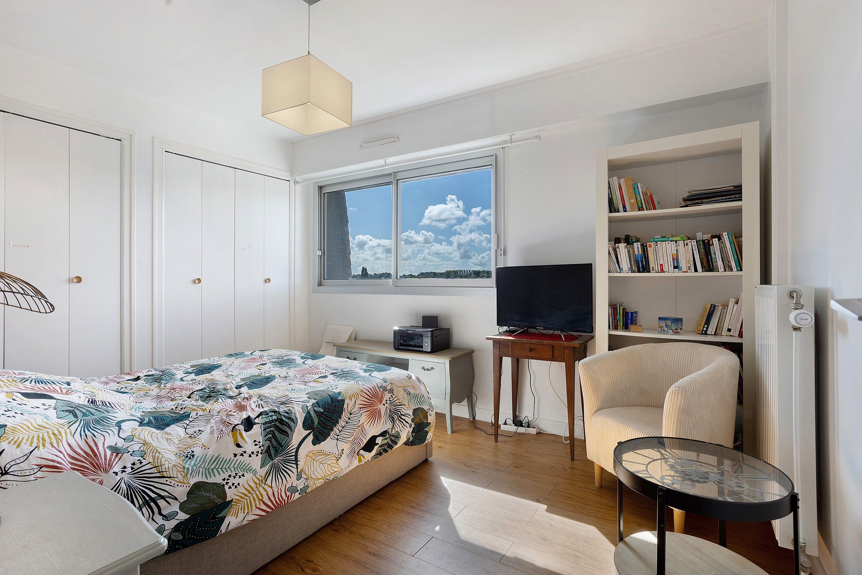 Un dormitorio con una cama, un escritorio, una silla, un televisor y una estantería.