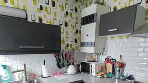 A modern kitchen with a microwave, kettle, and gas stove. - “Croas Men” Apartment with Sea View and Wi-Fi (Douarnenez)