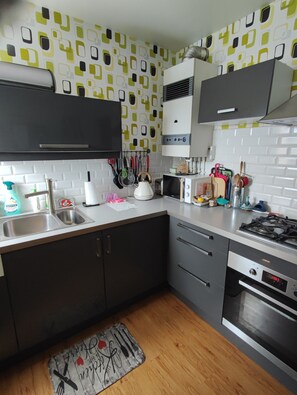 Une cuisine moderne équipée d’un four à micro-ondes, d’une bouilloire et d’une cuisinière à gaz.