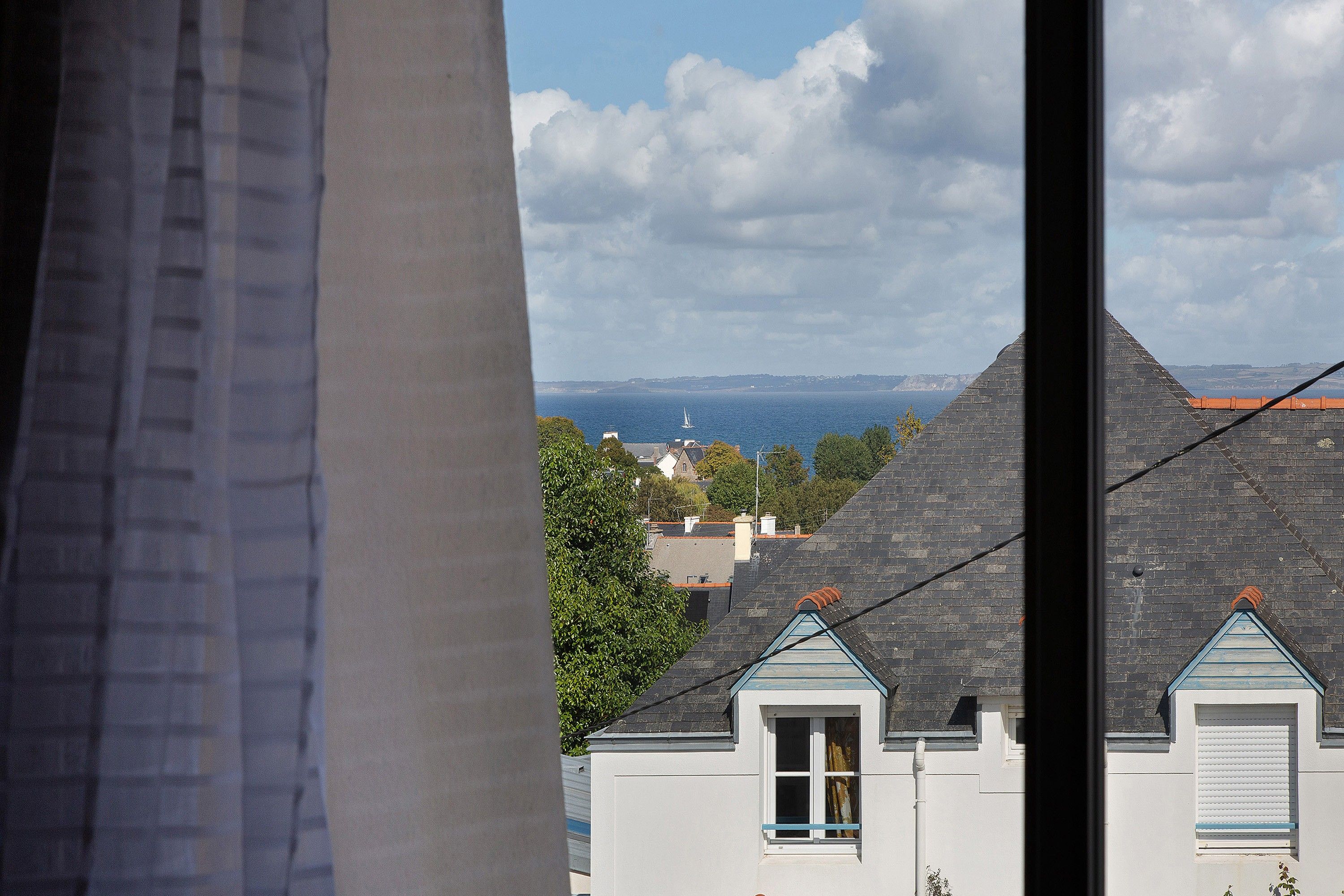 A coastal town with buildings, a clear sky, and a view of the sea.