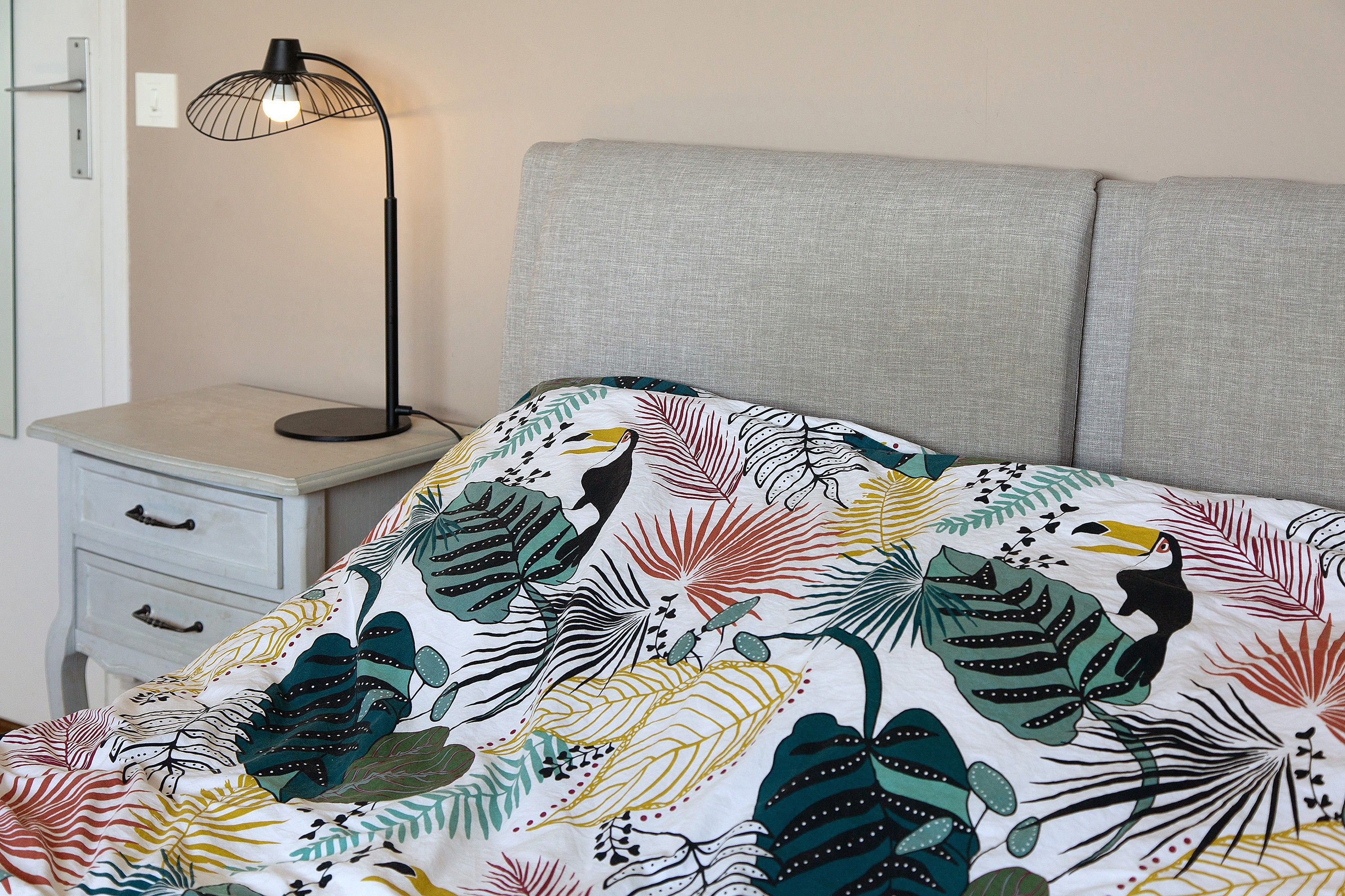 Ein Schlafzimmer mit einem Bett, einem Nachttisch und einer Lampe.