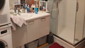 A bathroom with a glass-enclosed shower, a white sink with a mirror above it, and a washing machine. - “Croas Men” Apartment with Sea View and Wi-Fi (Douarnenez)
