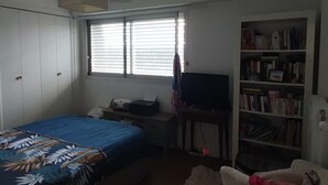 A bedroom with a bed, a desk, a bookshelf, and a window with blinds. - “Croas Men” Apartment with Sea View and Wi-Fi (Douarnenez)