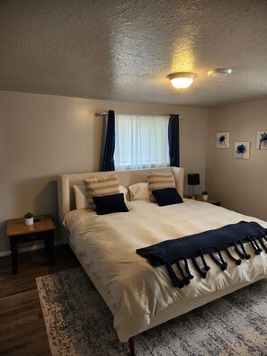 Ein Schlafzimmer mit einem Bett, Nachttischen, einer Fensterbank und Wandbildern.