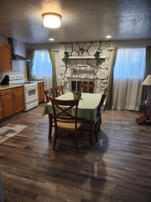 Ein Essbereich mit Kamin aus Stein, Holztisch und Stühlen.